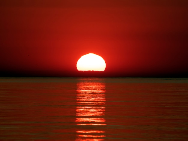 Coucher de soleil en mer en rouge avec reflet dans les petites vagues