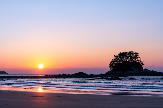 Coucher de soleil sur mer avec vagues et petite île