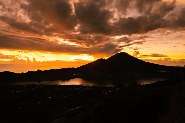 Un coucher de soleil sur le mont batur avec un volcan en arrière-plan