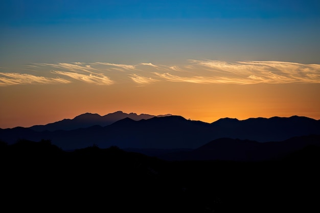 Coucher de soleil avec montagnes silhouettée et ciel bleu clair créé avec ai générative