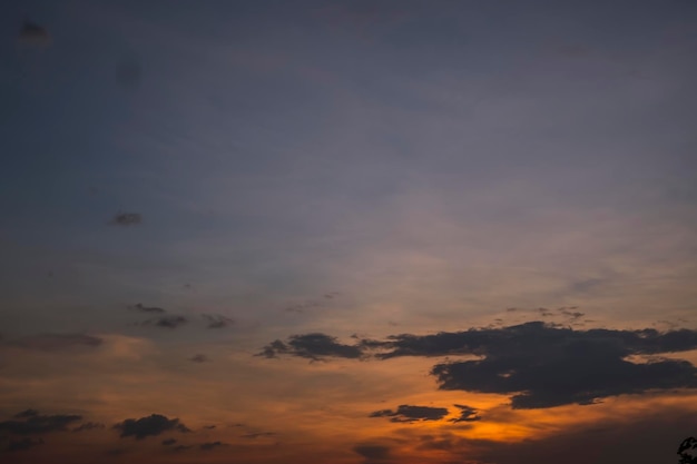 Un coucher de soleil avec des nuages et un ciel bleu avec un coucher de soleil jaune et orange.