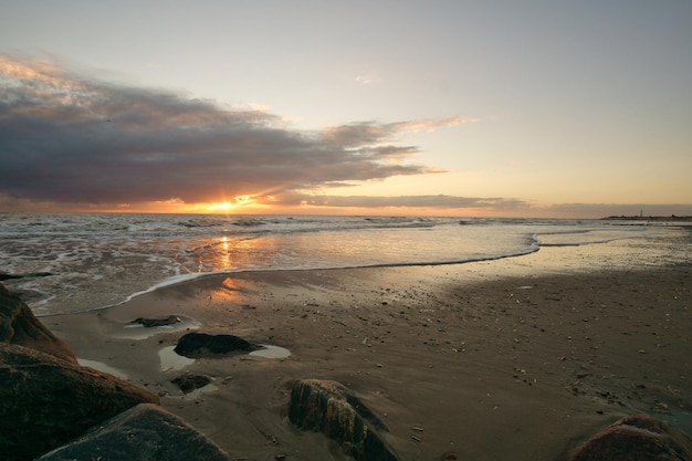 Coucher de soleil sur la plage au Danemark Pierres au premier plan Promenade sur la côte