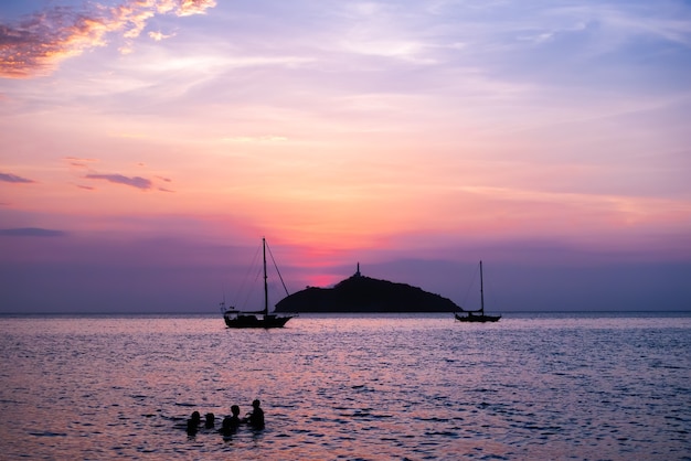 Coucher de soleil sur la plage avec un îlot dans le et les gens nagent