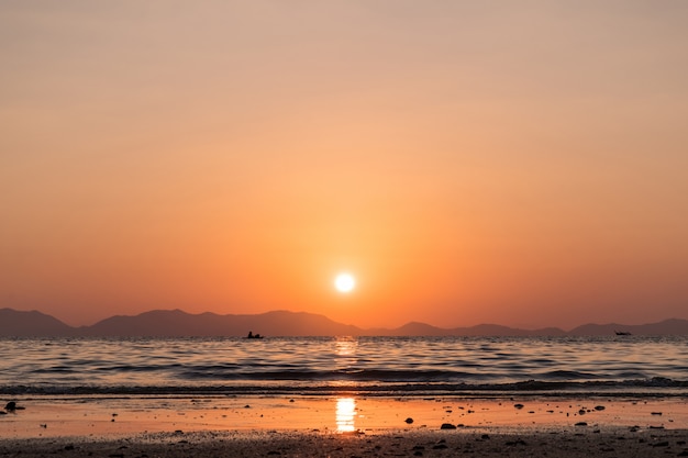 Coucher de soleil sur la plage et les montagnes à l'horizon