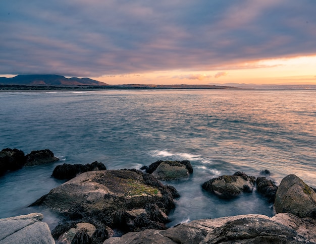 Coucher de soleil à la plage de Ritoque par temps nuageux avec une montagne à l'arrière