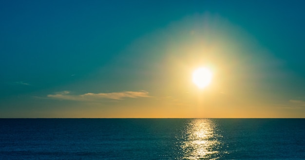 Coucher de soleil sur la plage avec soleil dans le ciel.