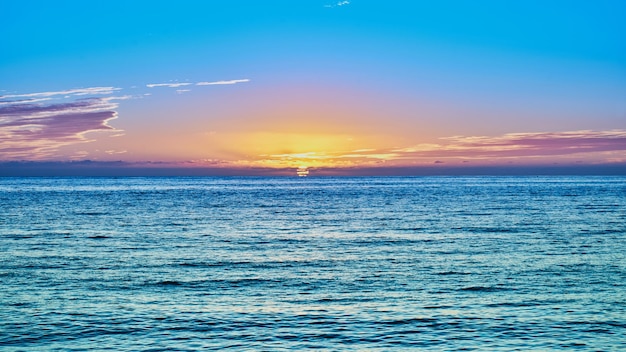 Photo coucher de soleil sur la plage et le soleil se couche à l'horizon