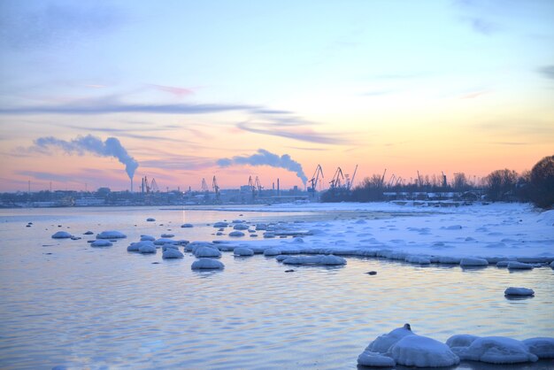 Coucher de soleil rose d'hiver et vue sur le paysage urbain au bord de la mer Baltique. Coucher de soleil avec rochers enneigés et paysage de plage. Mer Baltique, heure d'hiver