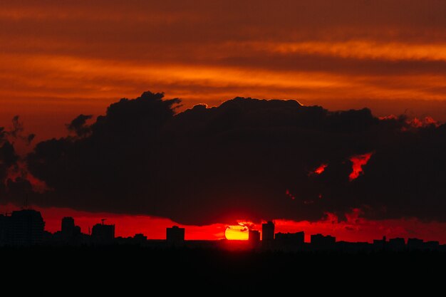 Coucher de soleil rouge et jaune sur la ville couverte de nuages.