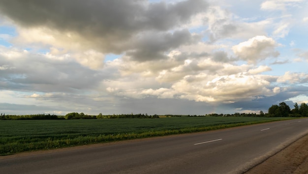 Coucher de soleil sur la route entre champs et prairies Beaux nuages Photo horizontale