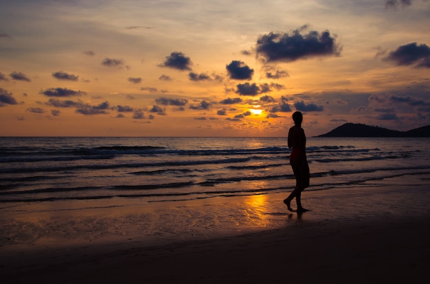 Coucher de soleil silhouette avec fille marchant sur la plage