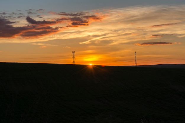 Coucher de soleil avec des silhouettes de pylônes électriques