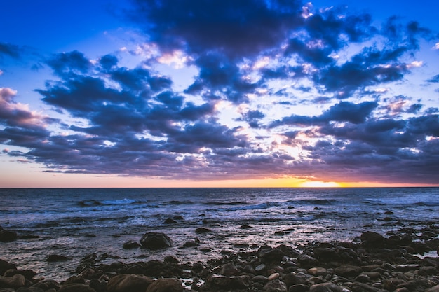 Coucher de soleil spectaculaire sur la plage rocheuse de Meloneras Îles Canaries Espagne Superbe crépuscule au bord de la mer