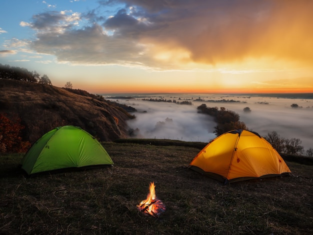 Coucher de soleil spectaculaire sur la rivière et les tentes avec un feu