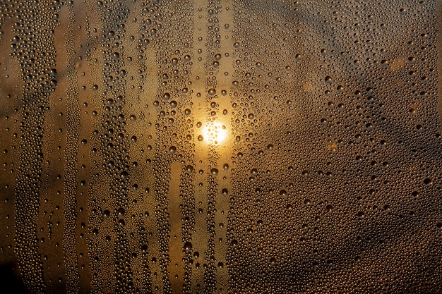 Coucher de soleil à travers un verre brumeux avec des gouttes et des gouttes