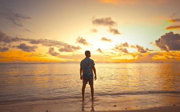 Coucher de soleil tropical face à l'océan sur une belle île. Homme en vacances profitant du moment