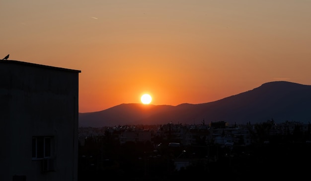 Coucher de soleil sur la ville Couleurs du soleil d'or orange rouge le ciel silhouette du bâtiment et pigeon au crépuscule