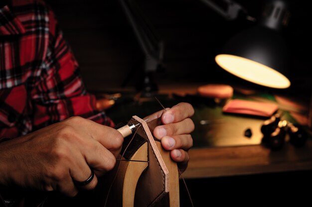 Coudre le cuir au tannage végétal à la main. Le cuir et les outils d'artisanat.