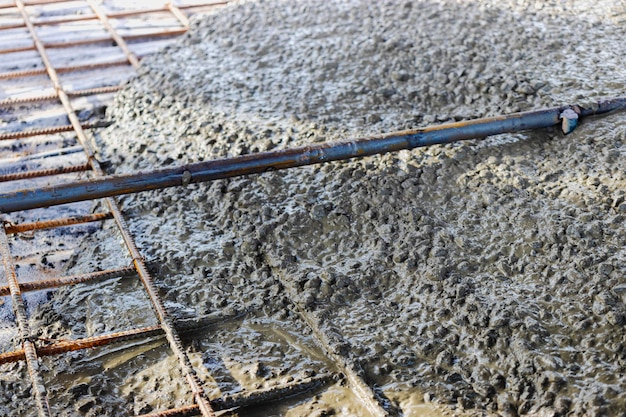 Coulage du sol renforcé avec du béton le long de guides métalliques. Fermer.