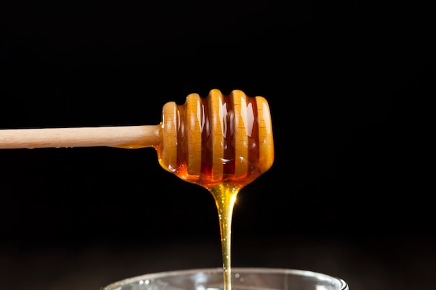 coulant épais et délicieux miel doux coulant dans un bocal en verre, un produit alimentaire naturel et sain créé par les abeilles, le miel d'abeille naturel a une consistance visqueuse et épaisse et s'écoule lentement dans le pa