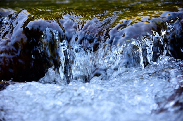 Écoulement d'eau et pulvérisation d'une pierre en gros plan Texture vagues bleues