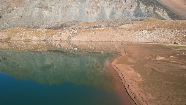 La couleur émeraude de l'eau d'un lac de montagne. Les montagnes et le ciel se reflètent