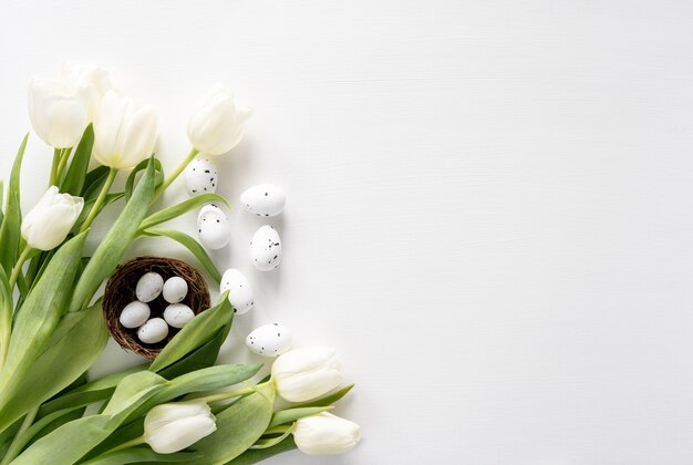 Couleur oeuf de Pâques et bouquet blanc de fleurs de tulipes sur fond blanc avec espace de copie.