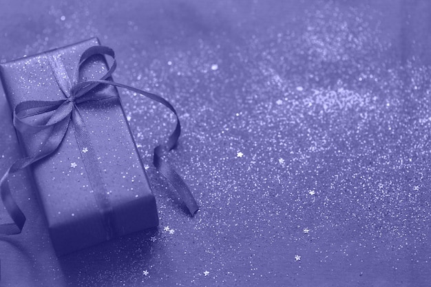 Couleur tendance de l'année 2022 Très péri. Cadeau violet ou coffret cadeau avec paillettes sur fond de couleur tendance. Notion festive. Vue de dessus.