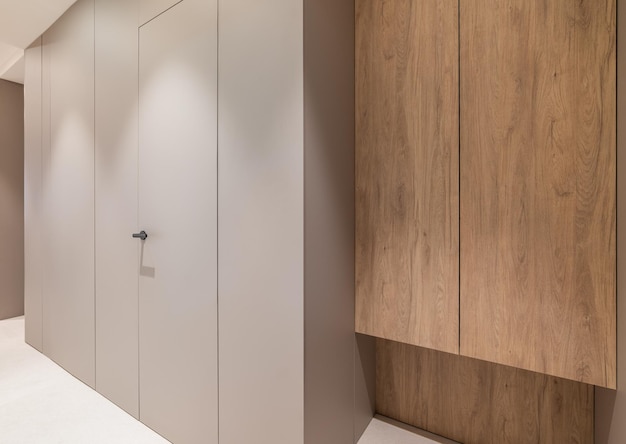 Couloir d'appartement avec armoire en bois et murs en panneaux gris avec porte