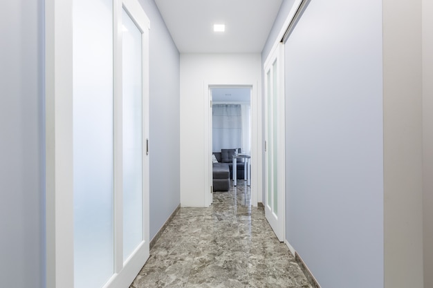 Photo couloir d'un petit appartement dans un style minimaliste moderne avec des portes coulissantes aux murs blancs et des carreaux de marbre noir au sol