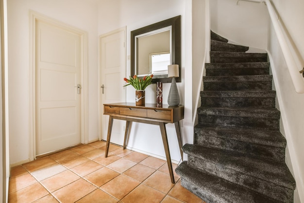 Un couloir spacieux avec des sols carrelés et un escalier recouvert de moquette menant à une maison confortable