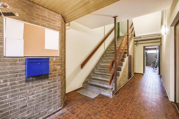 Un couloir spacieux avec des sols carrelés et un escalier recouvert de moquette menant à une maison confortable