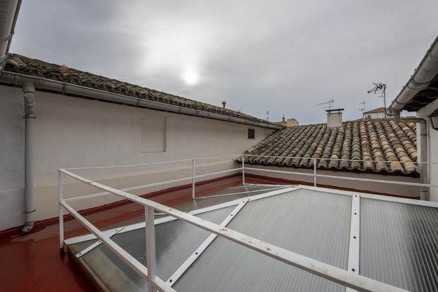 Couloirs d'un toit-terrasse avec accès aux toitures en terre cuite et lucarne en aluminium et méthacrylate semi-transparent