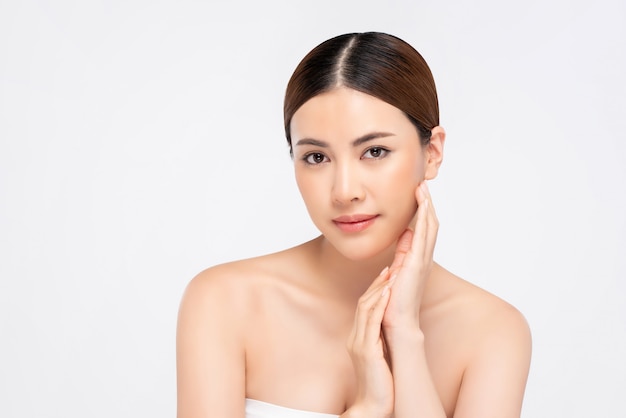 Coup de beauté de la peau lumineuse jeune jolie femme asiatique avec main touchant le visage