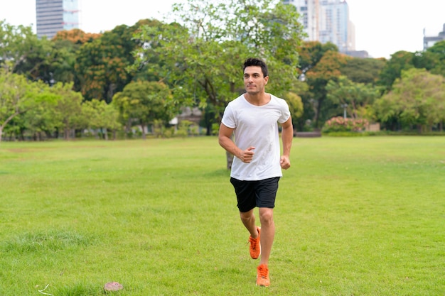 Coup de corps entier du jeune bel homme hispanique jogging dans le parc