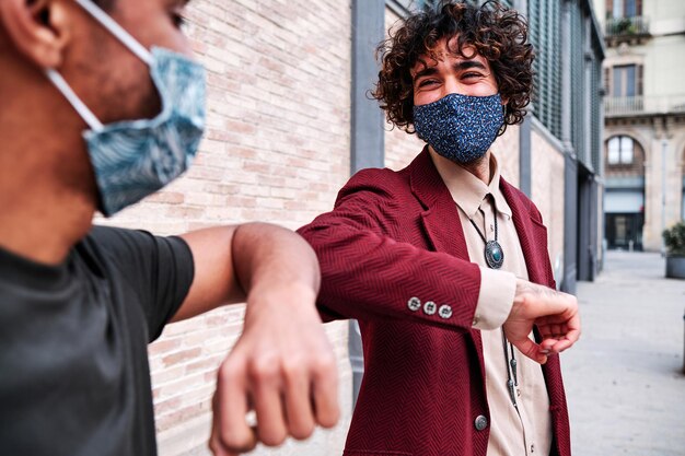 Photo coup de coude. salutation du coude pour éviter la propagation du coronavirus (covid-19). des hommes en chemise se rencontrent dans la rue à mains nues. au lieu de saluer d'une poignée de main ou d'un câlin, ils se cognent les coudes