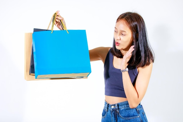 Coup de découpe en studio isolé d'une femme asiatique accro du shopping mère acheteuse portant des lunettes de mode souriant et portant des sacs en papier sur fond blanc