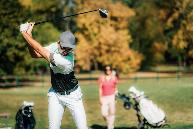 Photo coup de départ golf couple jouant au golf profitant d'une belle journée ensoleillée sur le terrain de golf