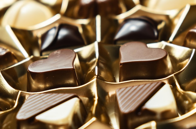 Coup de détail de deux chocolats en forme de coeur dans leur boîte dorée. Journée internationale du chocolat.