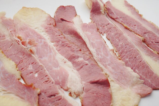 Coup de détail de lanières de bacon nourri cru sur fond blanc c