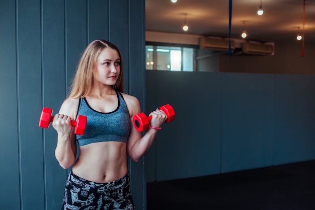 Coup de jeune femme s'exerçant avec des haltères au gymnase