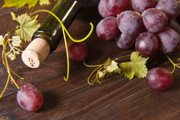 Coup de macro de raisins et bouteille de vin sur fond de planche de bois