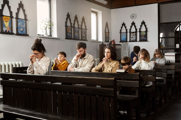 Coup moyen famille chrétienne priant à l'église