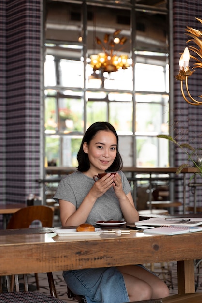 Coup moyen femme assise à table avec café