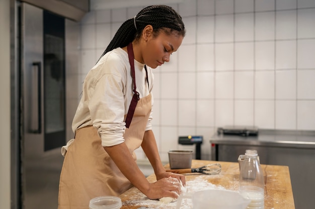 Coup moyen femme faisant cuire dans la cuisine