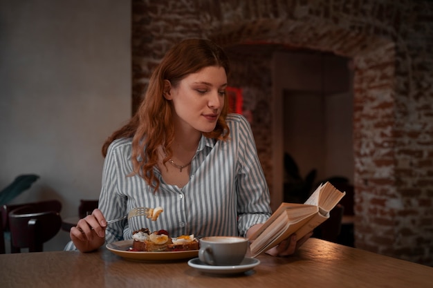 Coup moyen femme avec livre dans un café