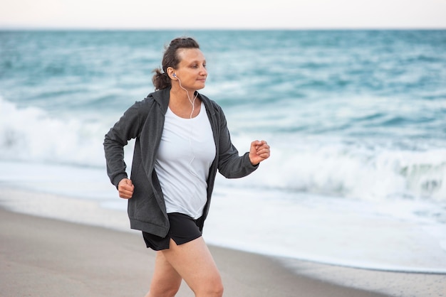 Coup moyen femme qui court sur le rivage