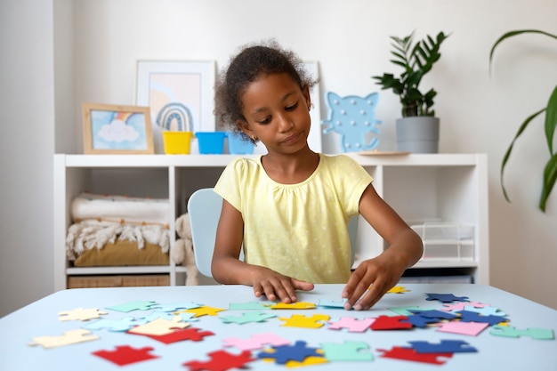 Photo coup moyen fille faisant un puzzle à table