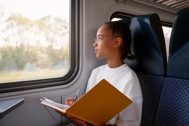 Photo coup moyen fille avec livre dans le train