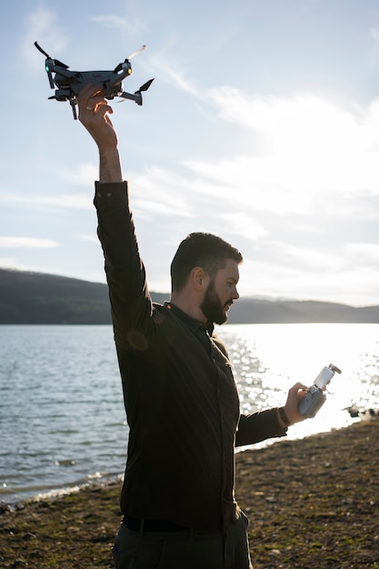 Coup moyen homme tenant un drone à l'extérieur